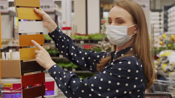Woman in a Protective Mask Chooses a Color of Paint for a Tree in a Hardware Store