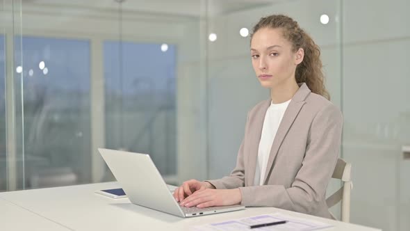 Disappointed Young Businesswoman Doing Thumbs Down in Office 