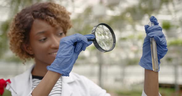 Young Female Scientist Holding Magnfier and Test Tube