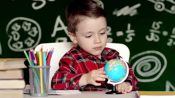 Home education for kids boy looking at globe. A child studies the globe at home. Teaching a child