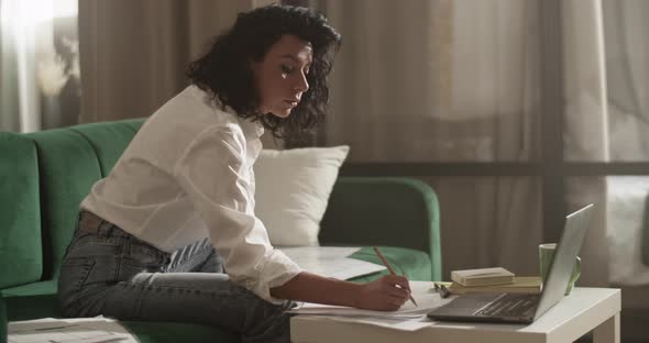 Female Entrepreneur Making Notes and Using Laptop