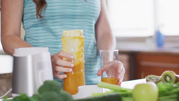 Caucasian woman drinking healthy drink in kitchen