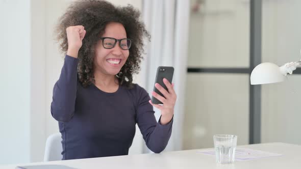 African Woman Celebrating Success While Using Smartphone