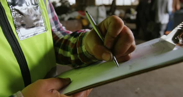 Male worker writing on clipboard in warehouse 4k