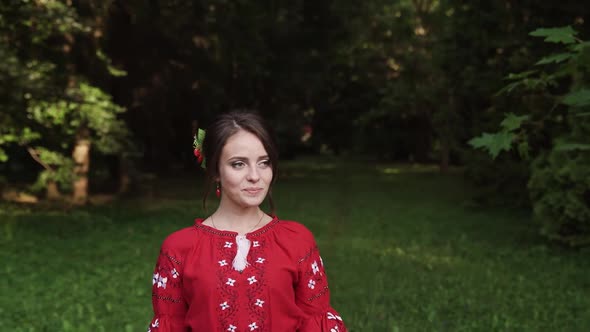 Portrait of an attractive brunette woman in red walking in the park and smiling.