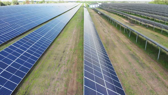 Aerial View of Solar Power Station. Panels Stand in a Row on Green Field. Summer