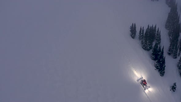 High Above Ski Slope View Of Snow Groomer Driving Over Snowfield To Improve Trail Conditions