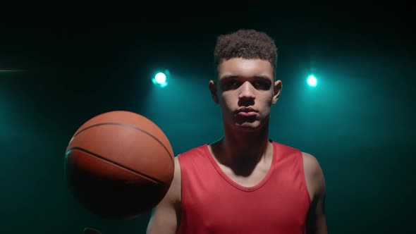 Portrait of Young Guy Basketball Player Looking at the Camera and Tossing the Ball Up