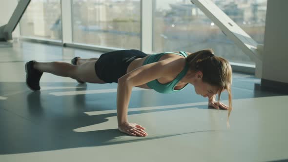 Slow Motion of Strong Young Woman Doing Pushups Exercising in Modern Sunlit Gym