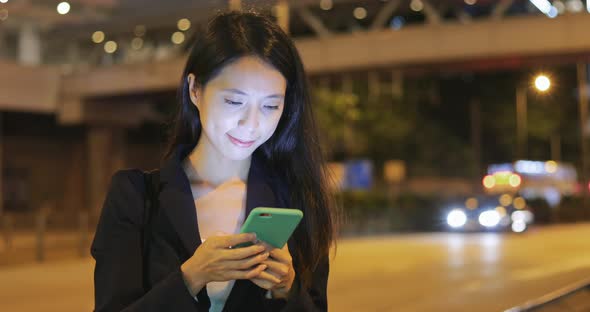 Business woman looking at mobile phone at night 