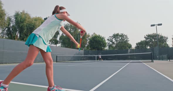 Girl in a Turquoise Dress Hits the Ground with the Ball Before Making a Serve