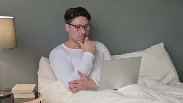 Pensive Middle Aged Man with Laptop Thinking in Bed 