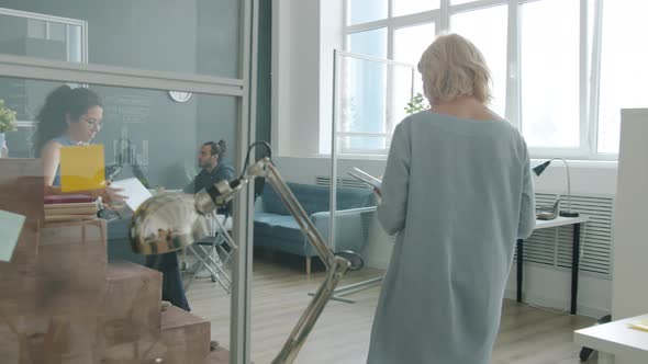 Slow Motion of Mature Businesswoman Walking in Office Then Watching Presentation with Digital Board