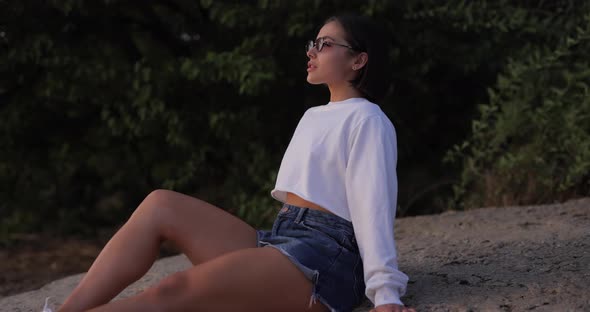 Pretty Woman Sitting on the Nature in Sunglasses