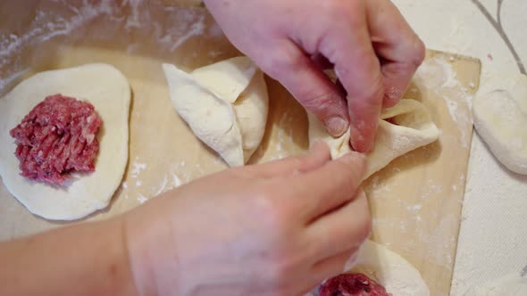 Female Hands Mold Triangular Pies with Meat Filling