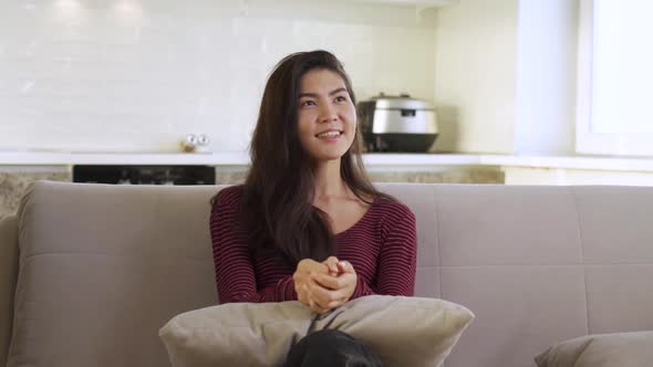 Portrait of a Happy Asian Girl Sitting at Home on the Couch