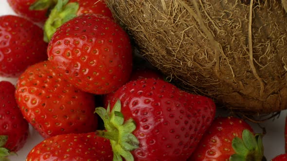 Tropical fruits coconut and strawberry rotates on a white background. Slow spinning exotic fruits