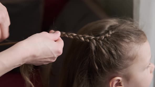 Mother Braids Daughter Pigtails on Hair Head