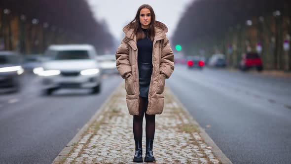 Time lapse of young woman standing in city street on autumn day looking at camera alone