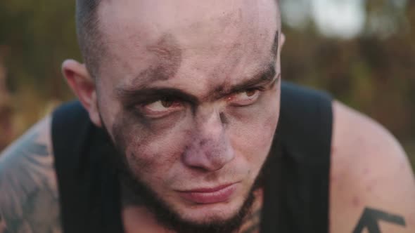 Brutal Athlete with Soot on Face and Tatoos Looking Aside and Into Camera