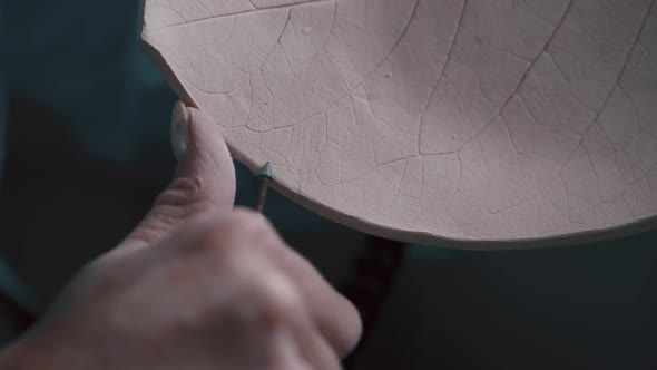 Potter Sanding the Rough Edges of a Plate That She Made From Clay