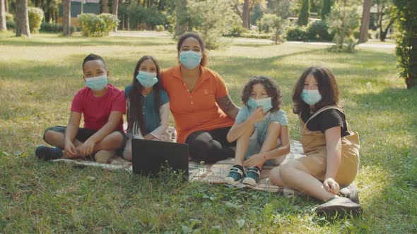 Schoolchildren and Teacher in Medical Protective Face Masks Outdoors