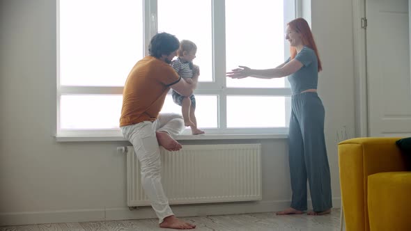 Happy Family Playing with Little Baby Son Running on the Windowsill