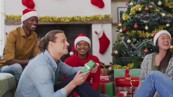 Happy diverse group of friends sharing with presents at christmas time