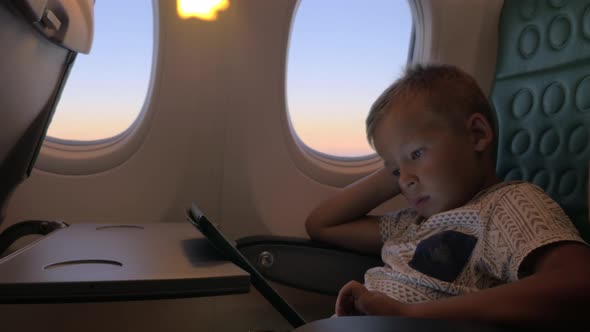 Bored kid with pad in plane