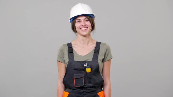 Portrait of Smart Young Woman Engineer or Builder in Helmet and Jumpsuit Laughing While Working on