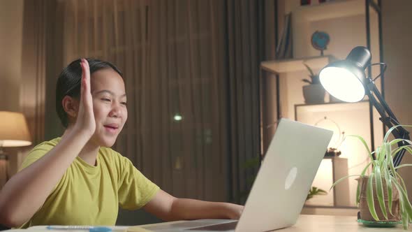 Asian Kid Girl Sitting In A Wheelchair While Video Call On Laptop Computer At Home