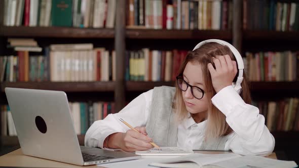 Tired Teen Girl Young Woman School Wear Headphones with Glasses Learn Watching Online Webinar