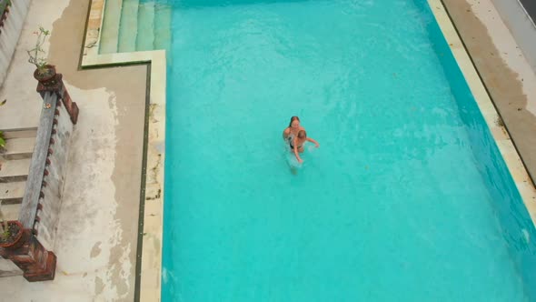 Slowmotion Aerial Shot of a Young Woman and Her Little Son Tourists Having a Good Time in a Swimming