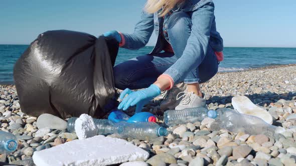 a woman collecting cleaning plastic bottles on the beach,