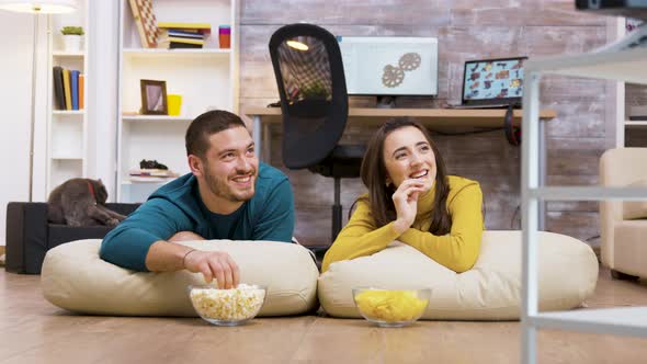 Cheerful Couple Watching Tv Sitting on Pillows