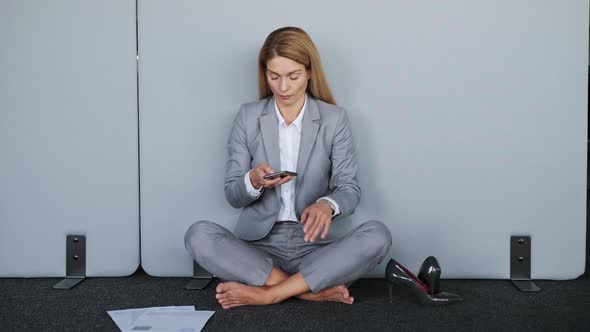 Stressed Business Woman Without Shoes Sending Message in Lotus Position