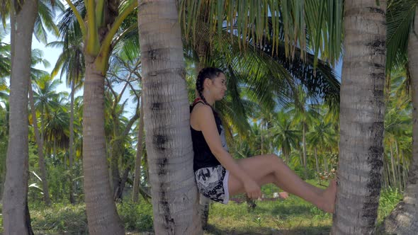 Beautiful Asian Girl Leaning Against Palm Tree Trunk on Tropical Beach