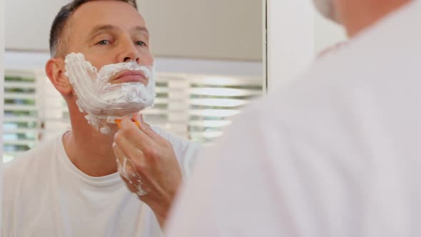 Man shaving his beard with razor in bathroom 4k