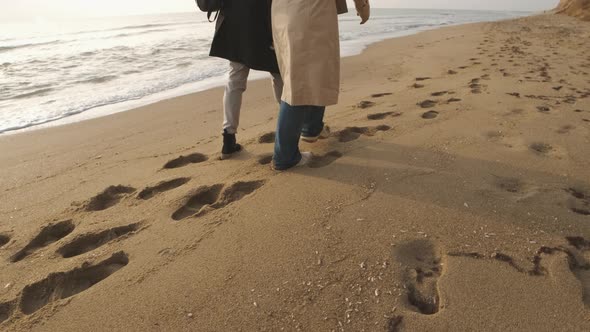 Happy Couple Walking on the Wild Beach on Cloudy Sunrise or Sunset