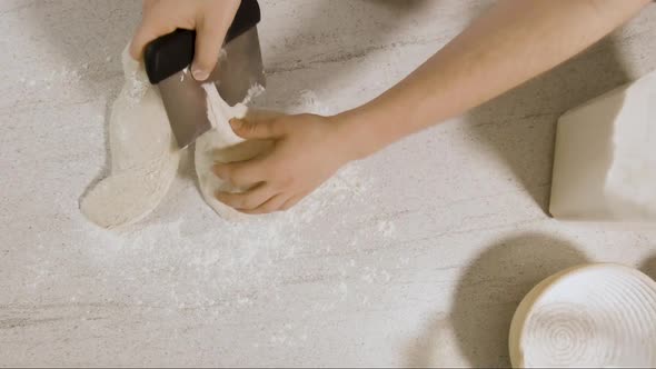 top down shot of Young Male Chef Forming Sourdough Dough on a kitchen side and placing it into a bak