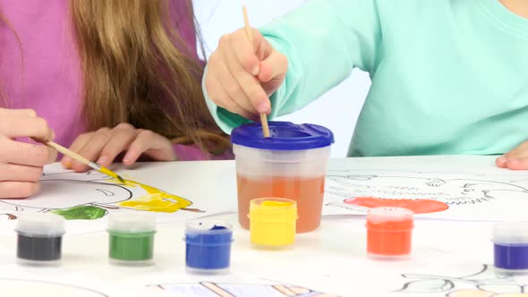 Small Children with the Help of Brushes and Paints Decorate Drawings, They Like It. Close Up. White