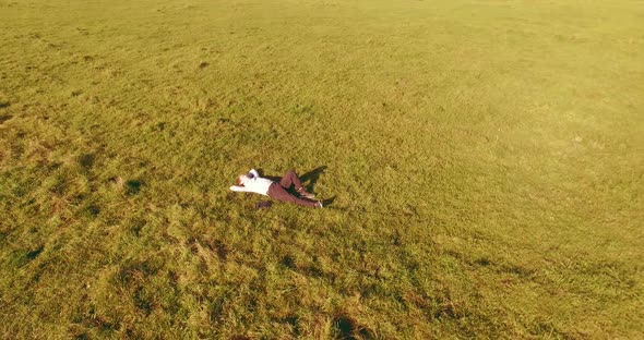 Low Orbital Flight Around Man with Notebook Pad at Yellow Rural Field