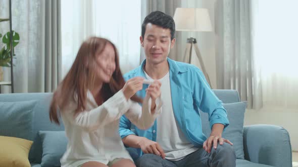 Happy Asian Couple After Checking A Pregnancy Test In Living Room At Home