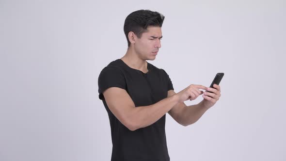 Happy Young Handsome Multi-ethnic Man Using Phone and Looking Surprised