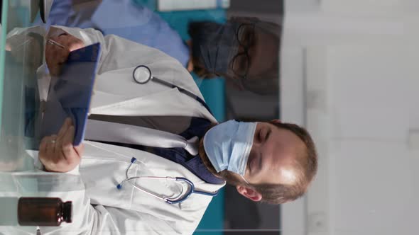 Vertical Video Male Physician Taking Notes on Checkup Files to Give Prescription