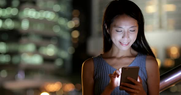 Woman using smart phone in Hong Kong city at night 