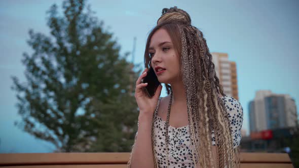 Young and Beautiful Girl Talking on a Smartphone in the Street