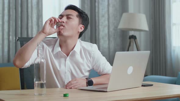 Asian Man Drinking Vodka From Glass During Having Video Call On A Laptop At Home