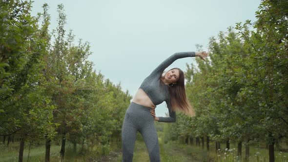 Woman Runner Stretching Arms Before Exercising Summer Park Morning Middle Age