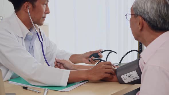 Doctor measuring blood pressure of elderly man in clinic.